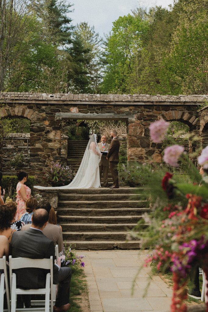 A bride in a Cathedral length veil exchanges vows with her groom in these ridley creek mansion wedding photos
