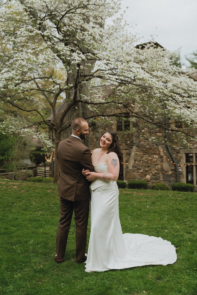 ridley creek mansion wedding photos display newlyweds beneath a flowering tree at Parque