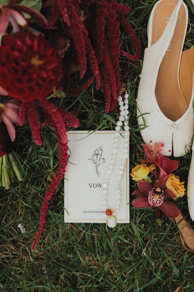 A bridal bouquet, vows, a pearl necklace, and bridal shoes are photographed at an american swedish historical museum wedding